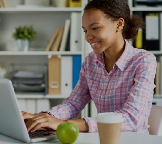 young person on laptop with coffee and apple