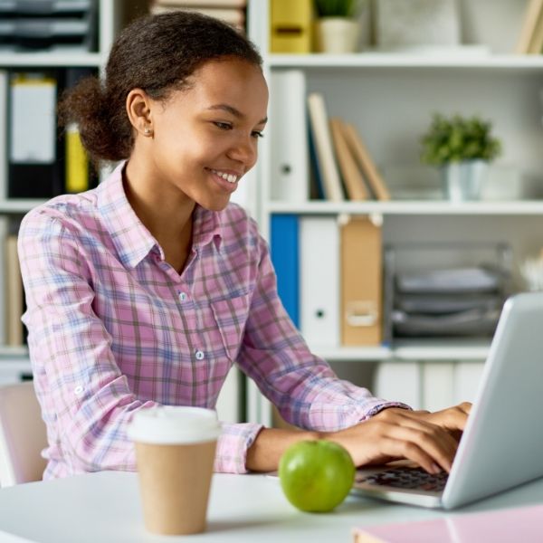 young person on laptop with coffee and apple